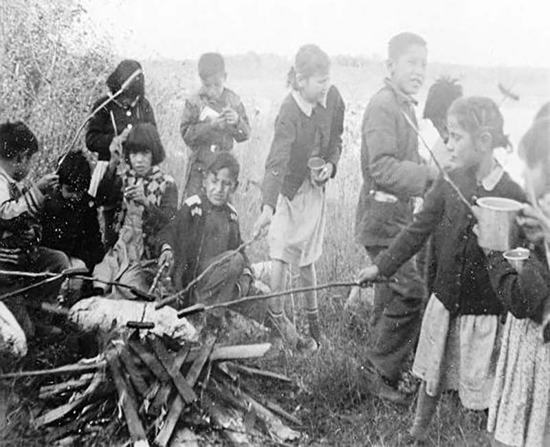 Group of children roasting hotdogs on fire at Gordon's school