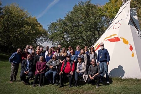group of NCTR staff and Survivors sitting and standing outside NCTR teepee