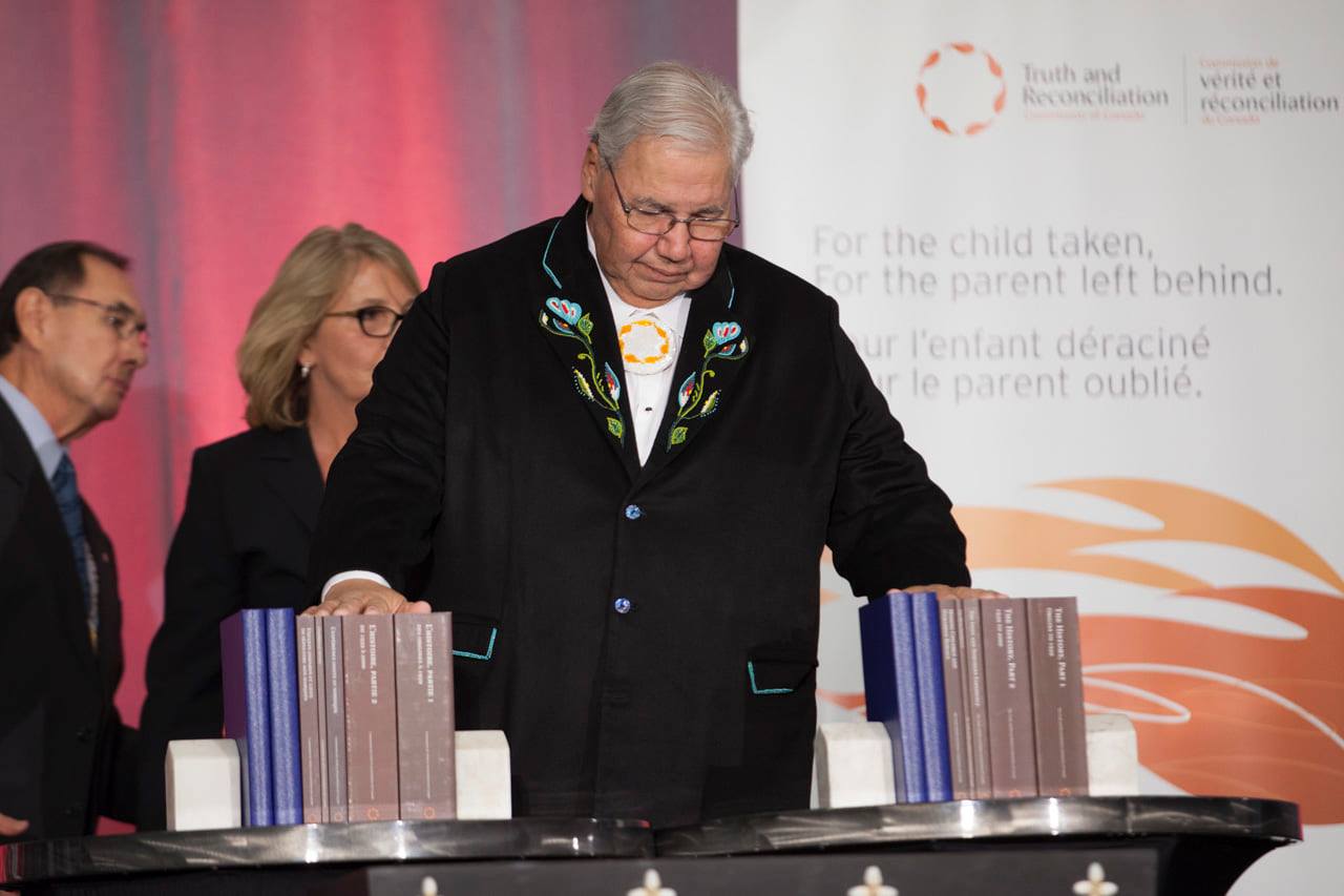 Person on stage with hands on report books at TRC closing ceremony