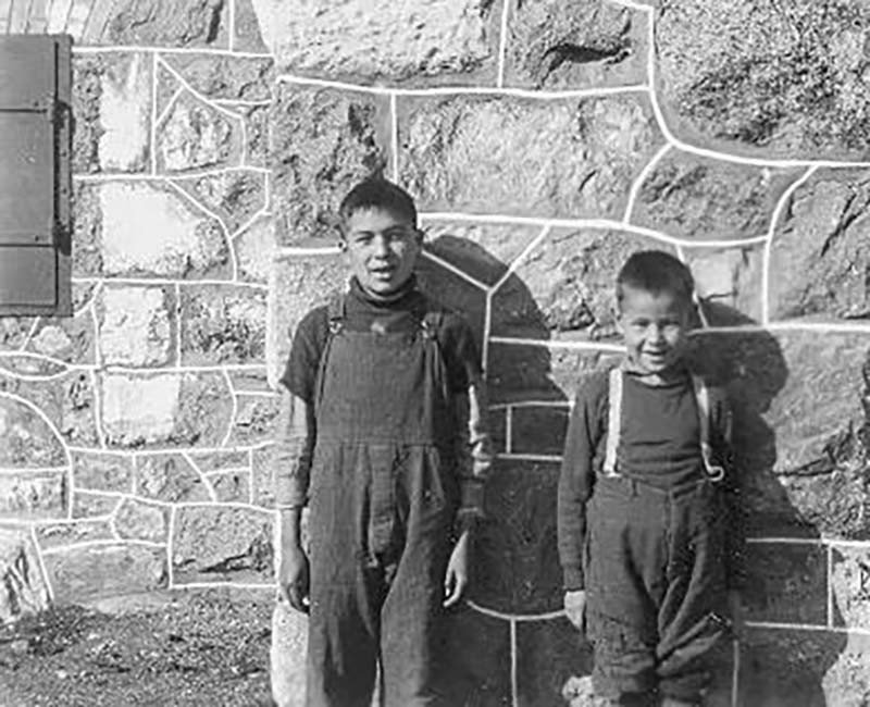 Two students leaning on a wall outside of Elkhorn school building
