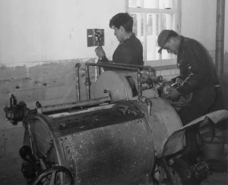 Two people fixing machine at Fort George Roman Catholic school