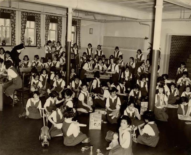 Group of students sitting in desks and on floor at Shubenacadie School