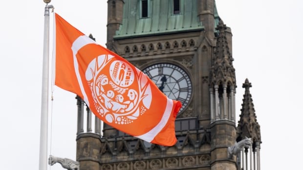 Close-up of the Survivors' Flag blowing in the wind on Parliament Hill, with the Peace Tower in the background.