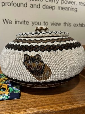 Un panier en perles avec un visage de loup sur le devant. Le panier contient les cendres mélangées de feux sacrés provenant de tous les événements nationaux de la CVR.