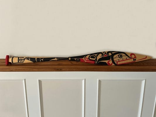 Une pagaie cérémoniale sculptée par l'artiste Carey Newman et peinte par le survivant des pensionnats Victor Newman, présentée en 2019 par l'Université de Victoria pour le Forum de construction de la réconciliation.